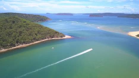 Beautiful-epic-aerial-view-of-a-speed-boat-passing-the-tropical-island-paradise-with-blue-turquoise-water