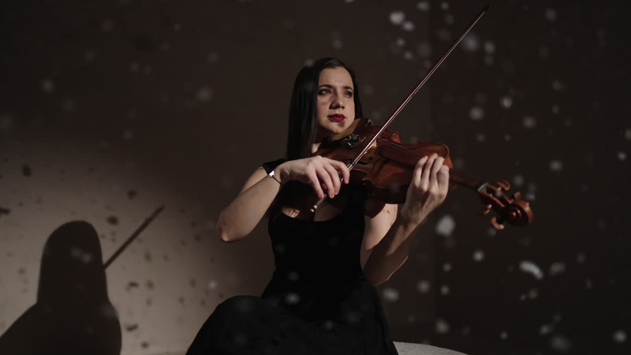 Violinist in a Black Dress Playing Violin in a Snow-filled Studio