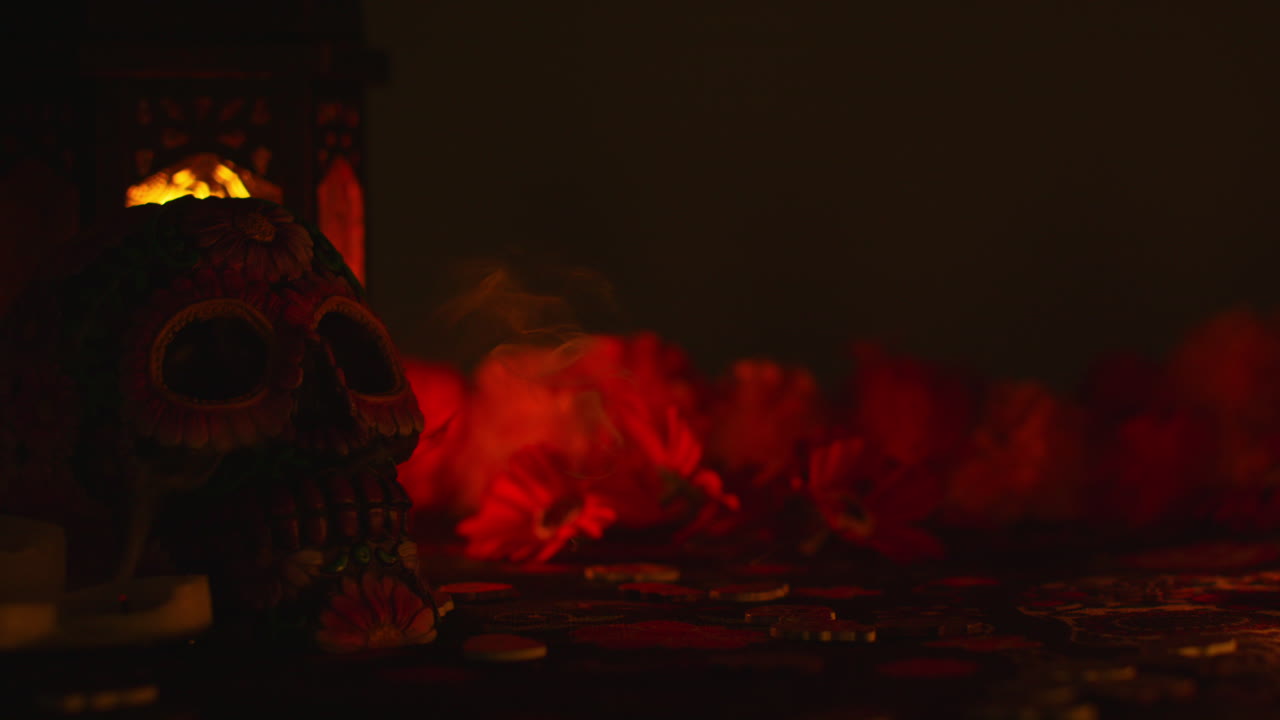 Candles Being Blown Out Next To Decorated Skull With Flowers Celebrating Mexican Holiday Of Dia De Muertos Or Day Of The Dead Against Dark Background