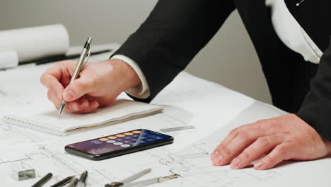 architect or engineer working on blueprints with smartphone calculator