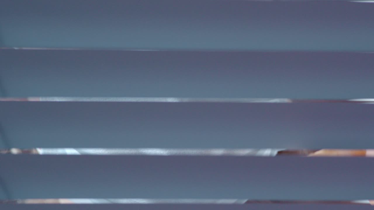 Woman looking through blinds while wearing a mask