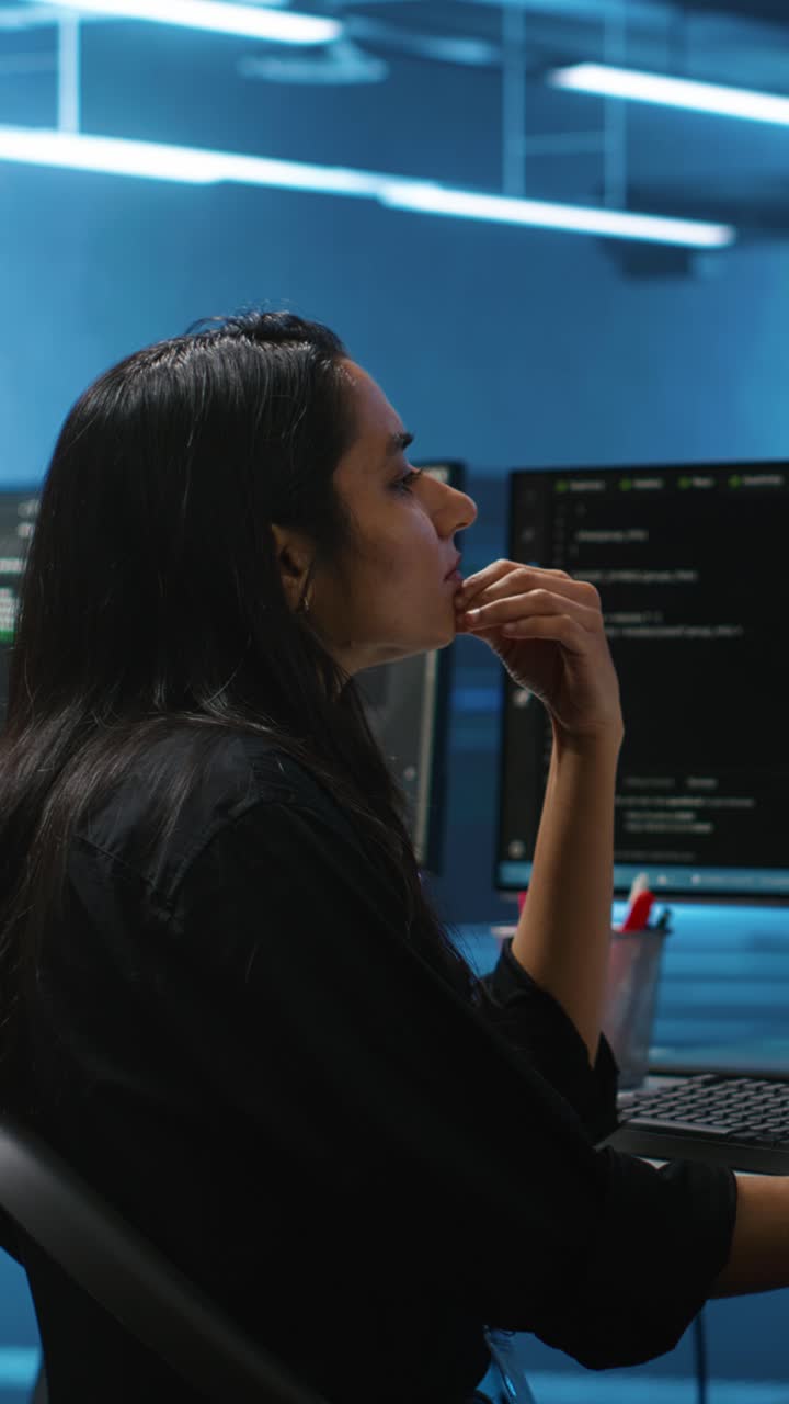 Focused Woman Developer Typing Code on Computer in Dark Office