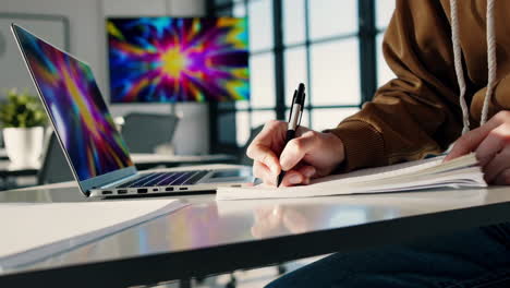 Student taking notes on a laptop in a modern office