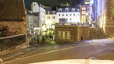 the gathering of people in front of a public building and the traffic on the road in the evening