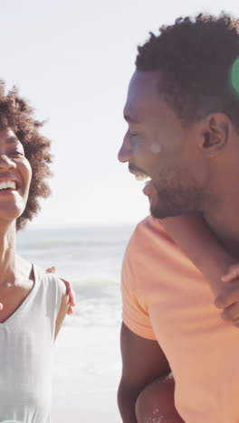 smiling african american family carrying and embracing on sunny beach