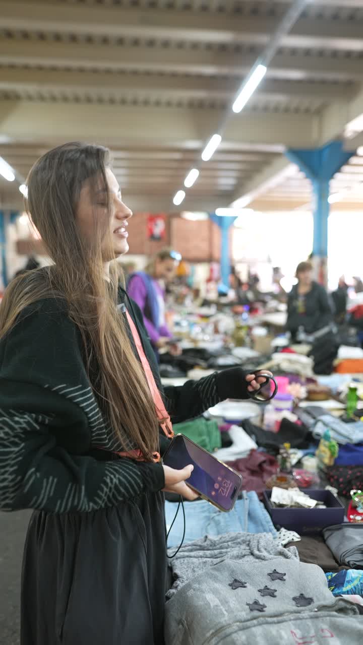 Donna che curiosa tra abiti usati in un mercatino delle pulci