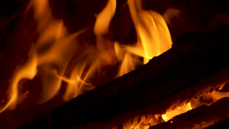 hot fire burning wooden logs in chiminea with bright orange flames in slow motion 4k