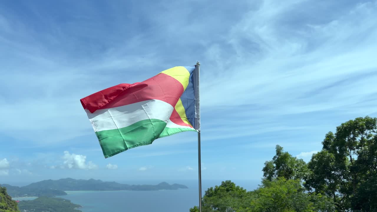 Bandiera nazionale delle Seychelles al rallentatore che sventola su una vista mozzafiato della costa occidentale di Mahé, isola di Mahé, Seychelles 25 fps 001