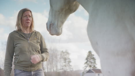 Woman-lets-feelings-go-and-interacts-with-white-horse-during-horse-therapy