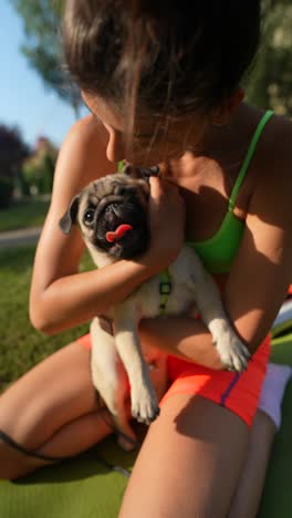 woman holding a pug dog in the park