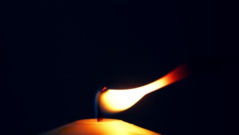 Single-big-yellow-candle-flame-lights-and-extinguish,-isolated-on-a-black-background