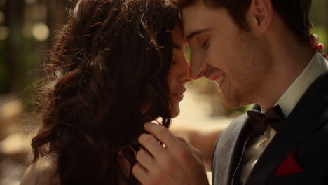 Novio-Guapo-Tocando-El-Pelo-De-La-Novia-Al-Aire-Libre.-Pareja-Sonriente-Posando-Bajo-El-Arco