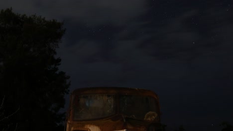 starry sky over a rusty, abandoned bus at night