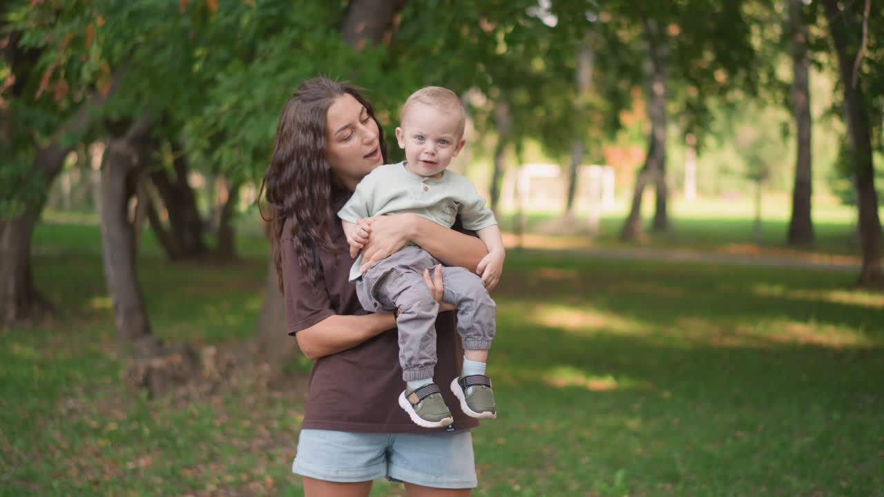 Madre e bambino che esplorano uno spazio esterno soleggiato. La madre porta a spasso il suo bambino in un vivace parco. Gita in famiglia con madre e figlio piccolo impegnati in una passeggiata giocosa all'aperto.