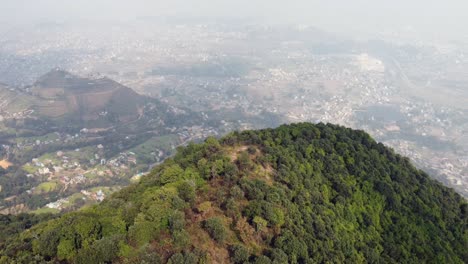 volando sobre el borde de una montaña para revelar el valle y la ciudad debajo