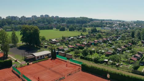 aerial drone shot of sunny day in gardening colony with tennis court, cabins, huts and shacks in the middle of city