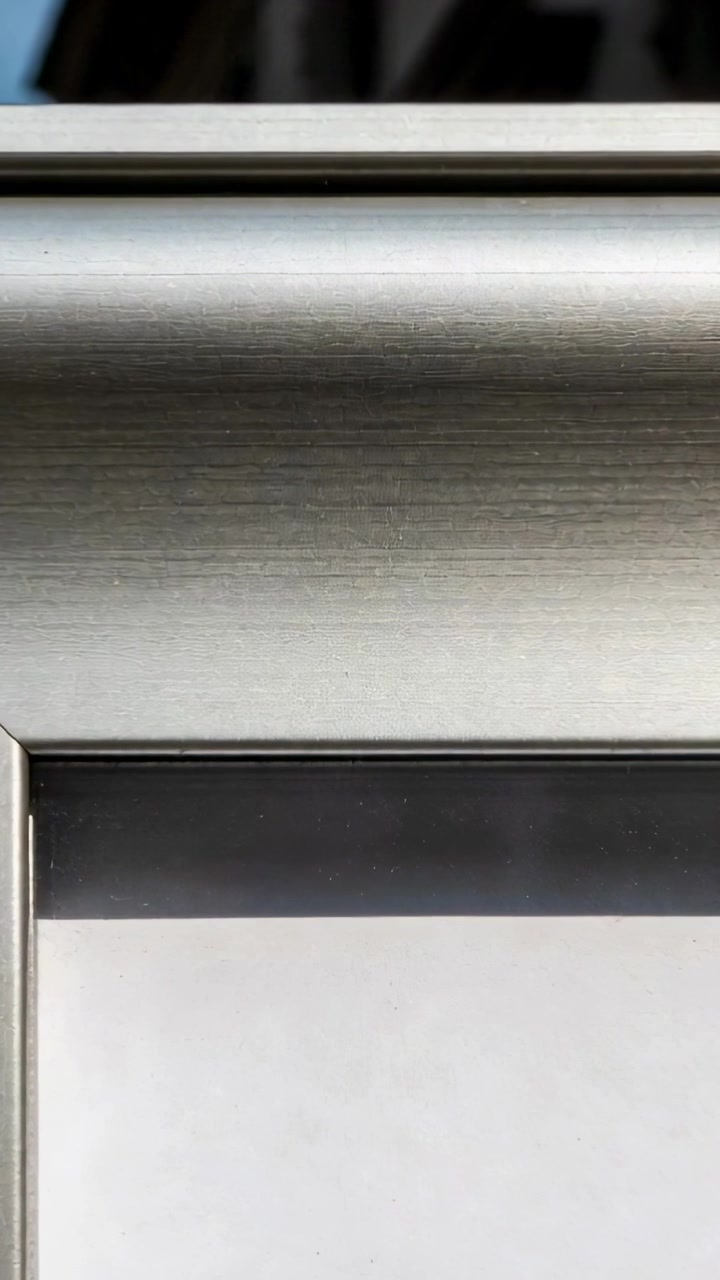 Video verticale: Telecamera che cattura un primo piano di modanatura metallica e angolo di cornice per registrare i cambiamenti di luce.