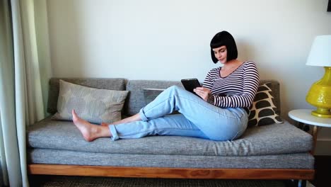 woman using digital tablet on sofa at home 4k