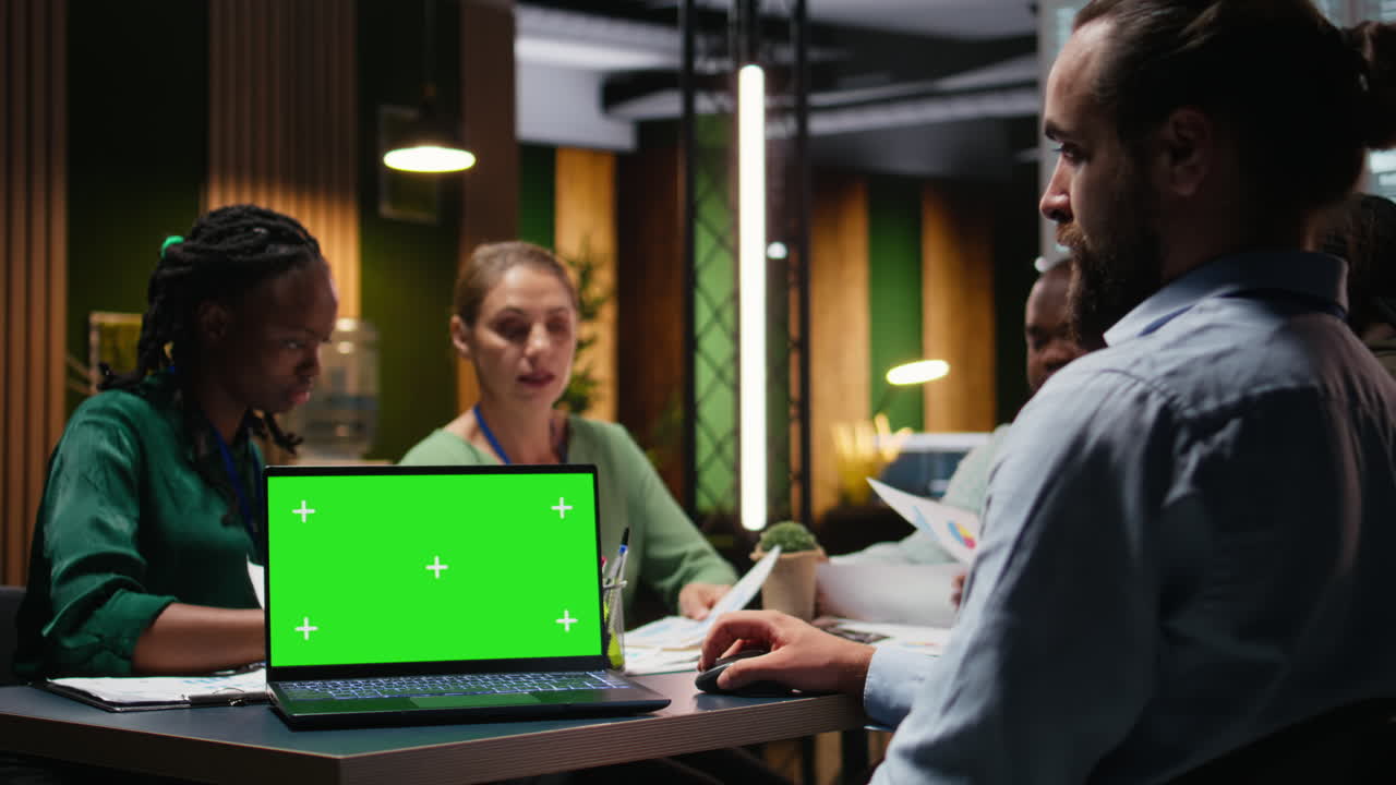 Diverse project team meeting after hours next to mockup display