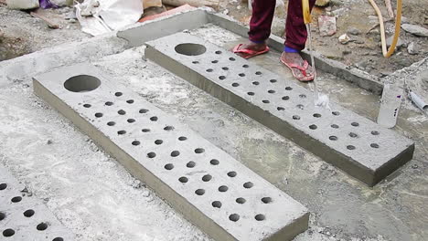 indian mason worker pouring water on fresh concrete slab to strengthen and smoothen it for construction