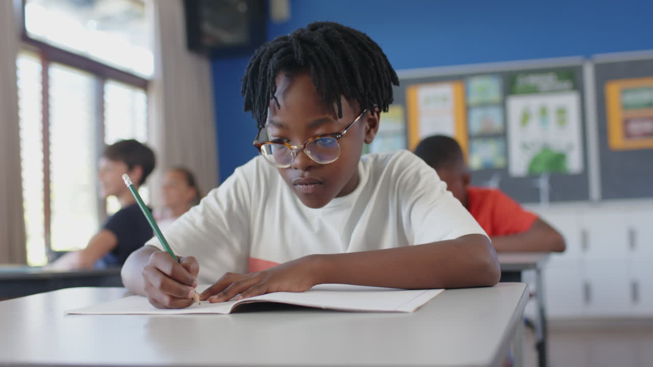 In school, boy writing in notebook at desk, concentrating on work