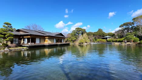 traditional japanese house by peaceful pond under clear blue sky, tranquil setting