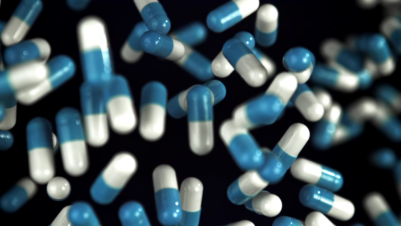 Capsule farmaceutiche blu e bianche che cadono su sfondo scuro