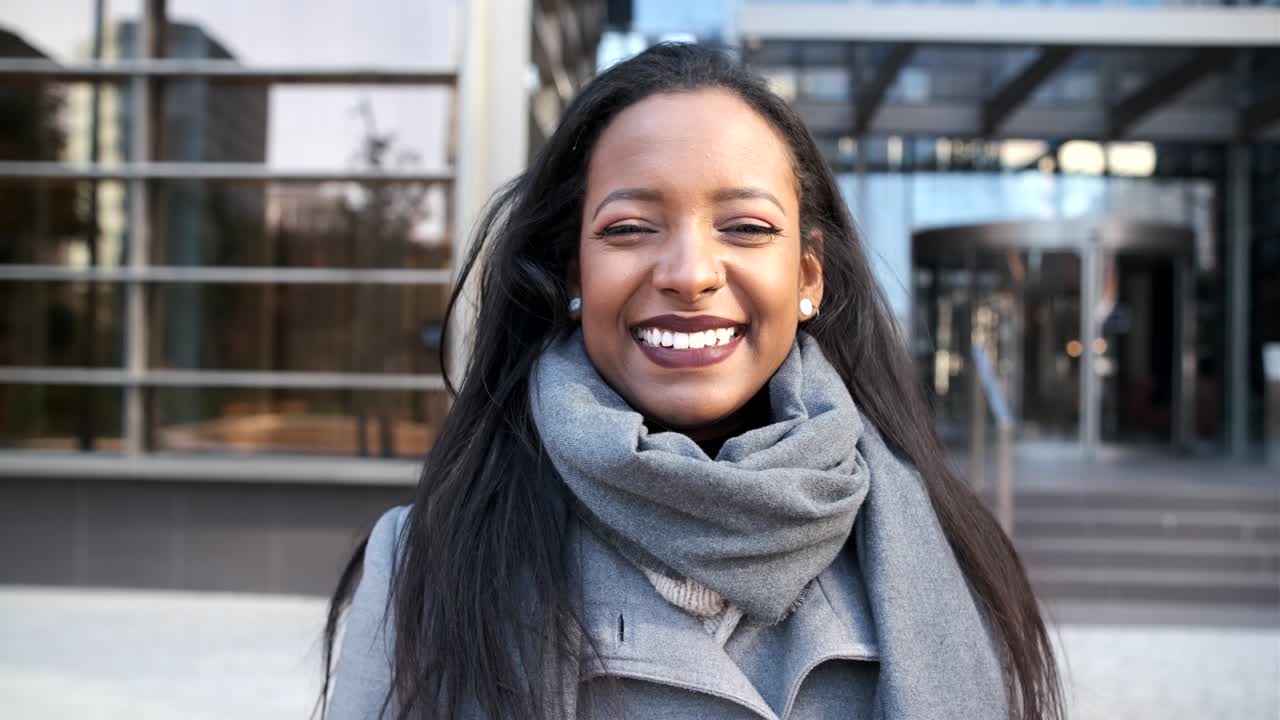 una mujer de negocios seria posando contra un edificio de oficinas en el distrito financiero.