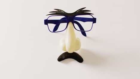 video of attached plastic eyebrows, glasses, nose and moustache on white background with copy space