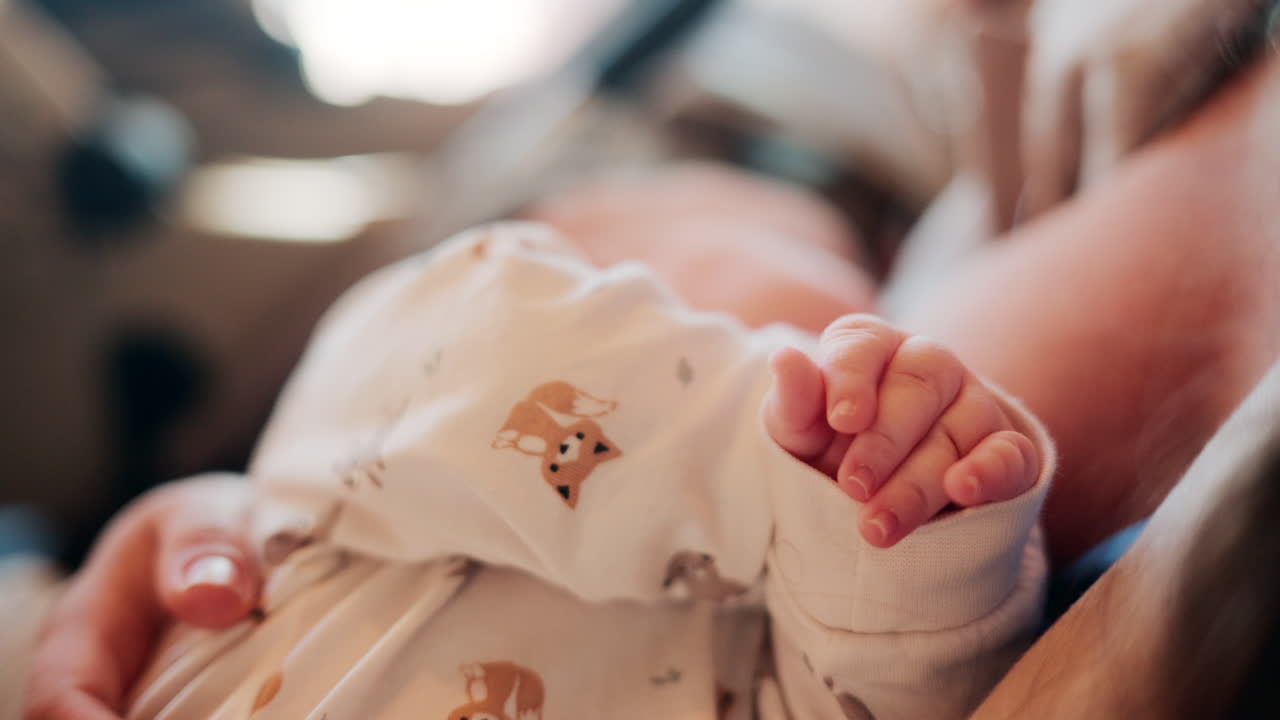 Tender moment of a mother holding her newborn baby dressed in patterned white pajamas