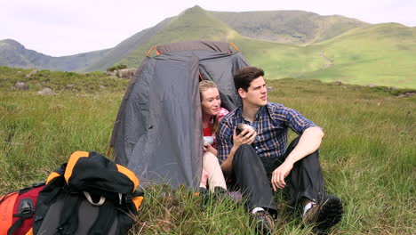 couple drinking soup in their tent and talking