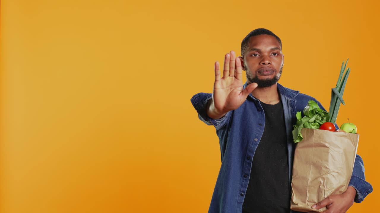 persona vegana mostrando una señal de parada con su palma mientras lleva una bolsa