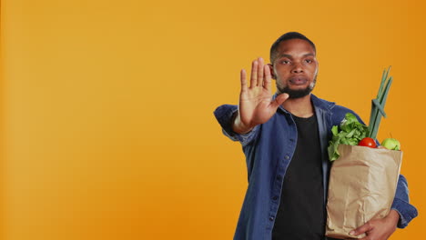 vegan person showing a stop sign with his palm while he carries a bag