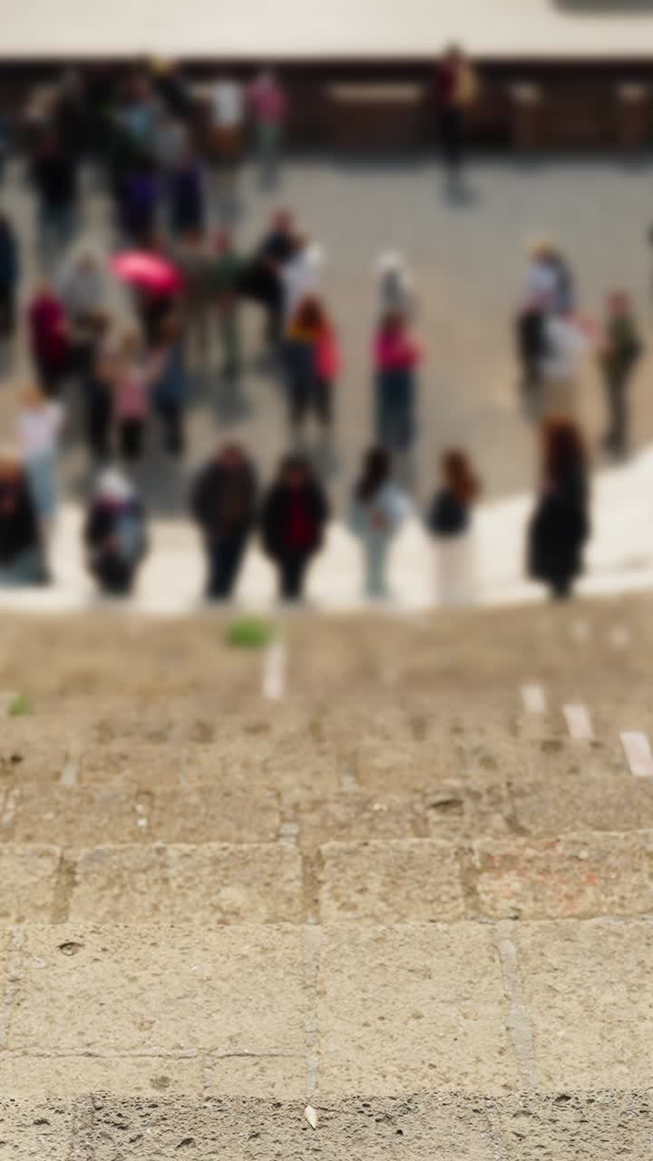 Turisti sfocati riuniti oltre antiche sedute in pietra a Pompei, Italia, creando una vista editoriale dei visitatori all'interno del sito archeologico romano in formato verticale.