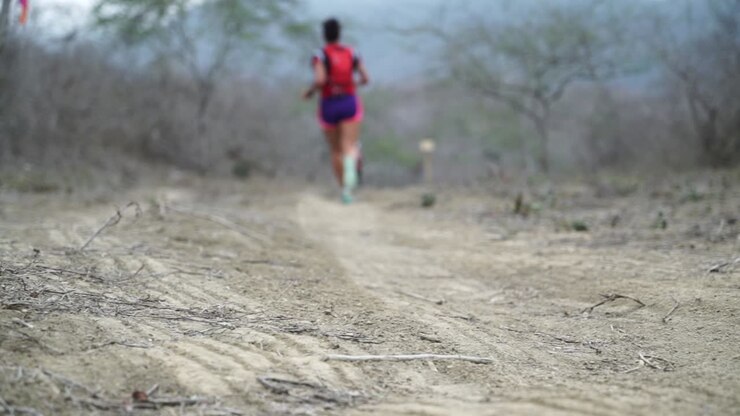 Marathon athlete is running very fast on dirt road through rural nature of Ecuador heading towards the finish line trying to catch up heavy work out slowmotion 25 fps