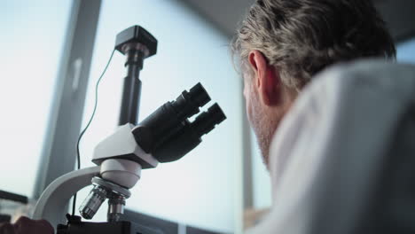 científico usando el microscopio en un laboratorio