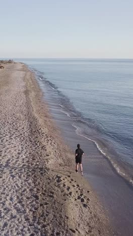 young runner man training on beautiful sunset at beach. drone tracking
