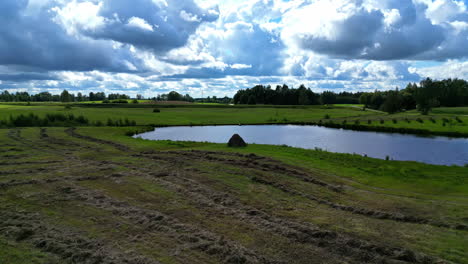 tranquil pond and countryside fields against cloudy sky - drone shot