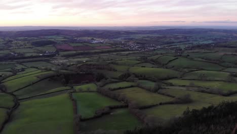 aerial view of green fields and hedges covering rolling hills in the english countryside near sidmouth at sunset