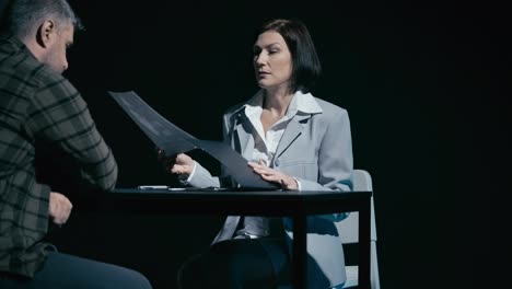 Female police detective showing crime scene photo to man, suspect denying guilt