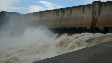 massive dam with water rushing from spillways