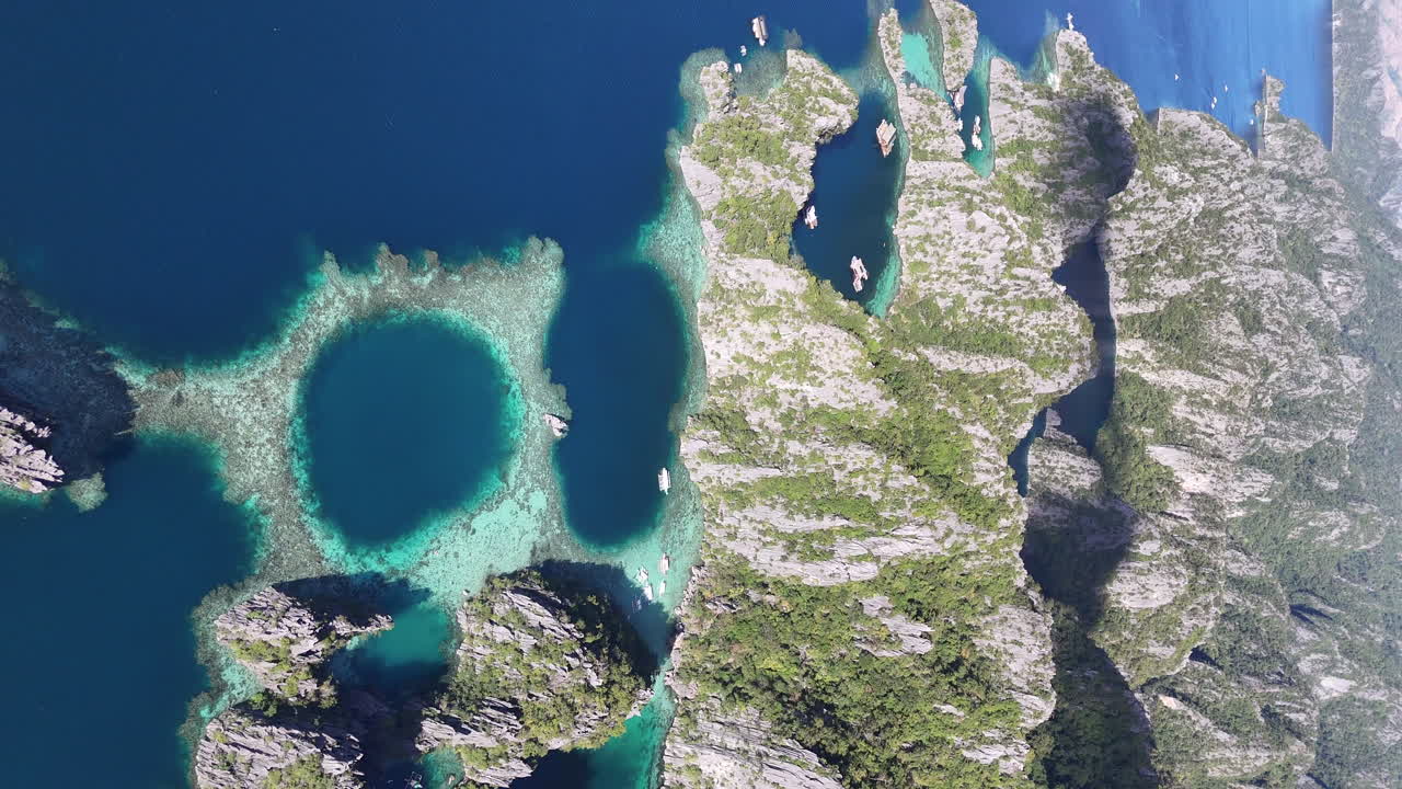 Drone view of Philippines, Coron Island’s untouched coastline, surrounded by lush forests and clear waters. Aerial view of boats and lagoon. Wide shot. Vertical video.
