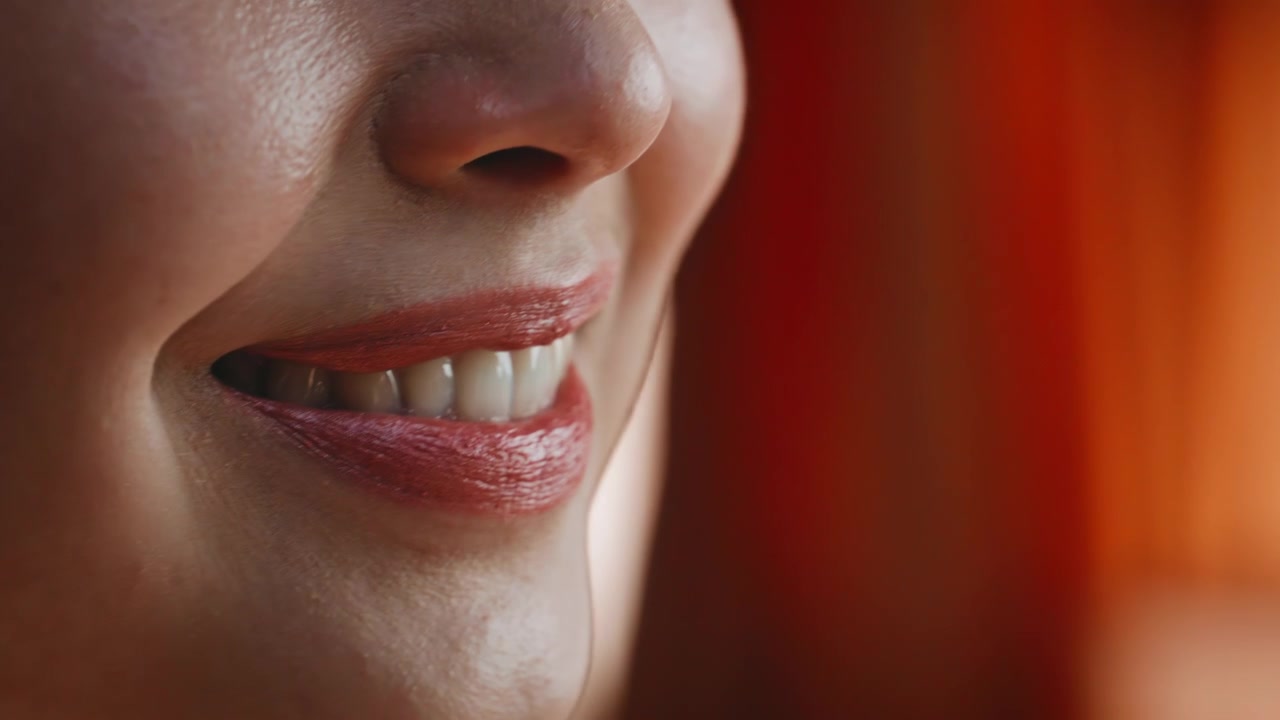 Close up woman applying red lipstick lips. Macro beauty makeup orange light.