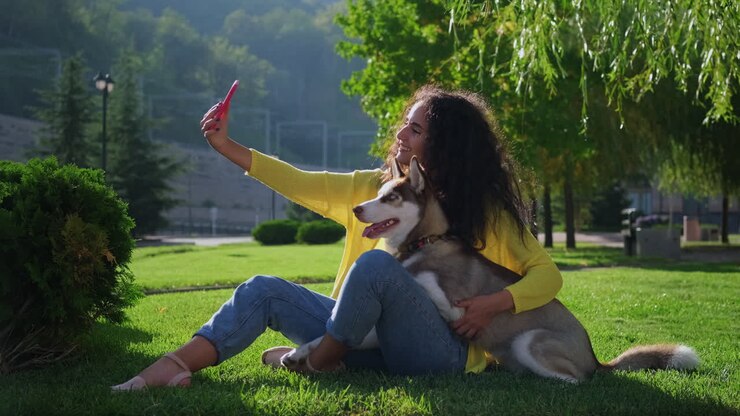 Woman taking selfie with her husky dog in a park