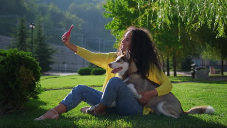 woman taking selfie with her husky dog in a park