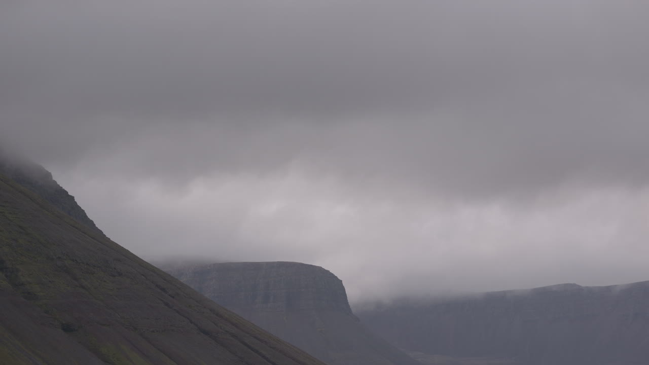 Dense clouds moving over mountain tops in the Icelandic fjords near Isafjordur, Iceland