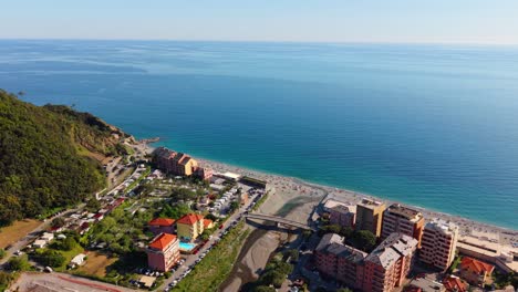 beautiful sunny coastal town in italy with beach and mountain backdrop, aerial view