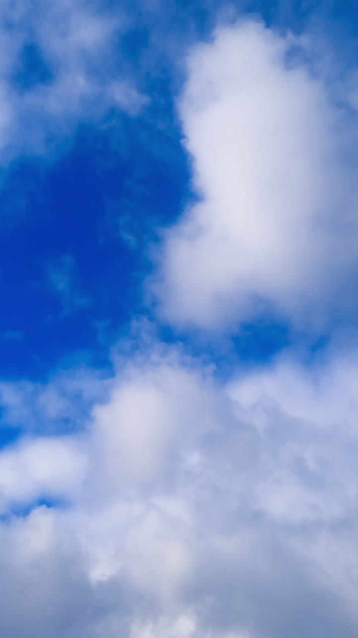 Blue sky with clouds flowing over. Timelapse of fluffy clouds motion. Vertical video