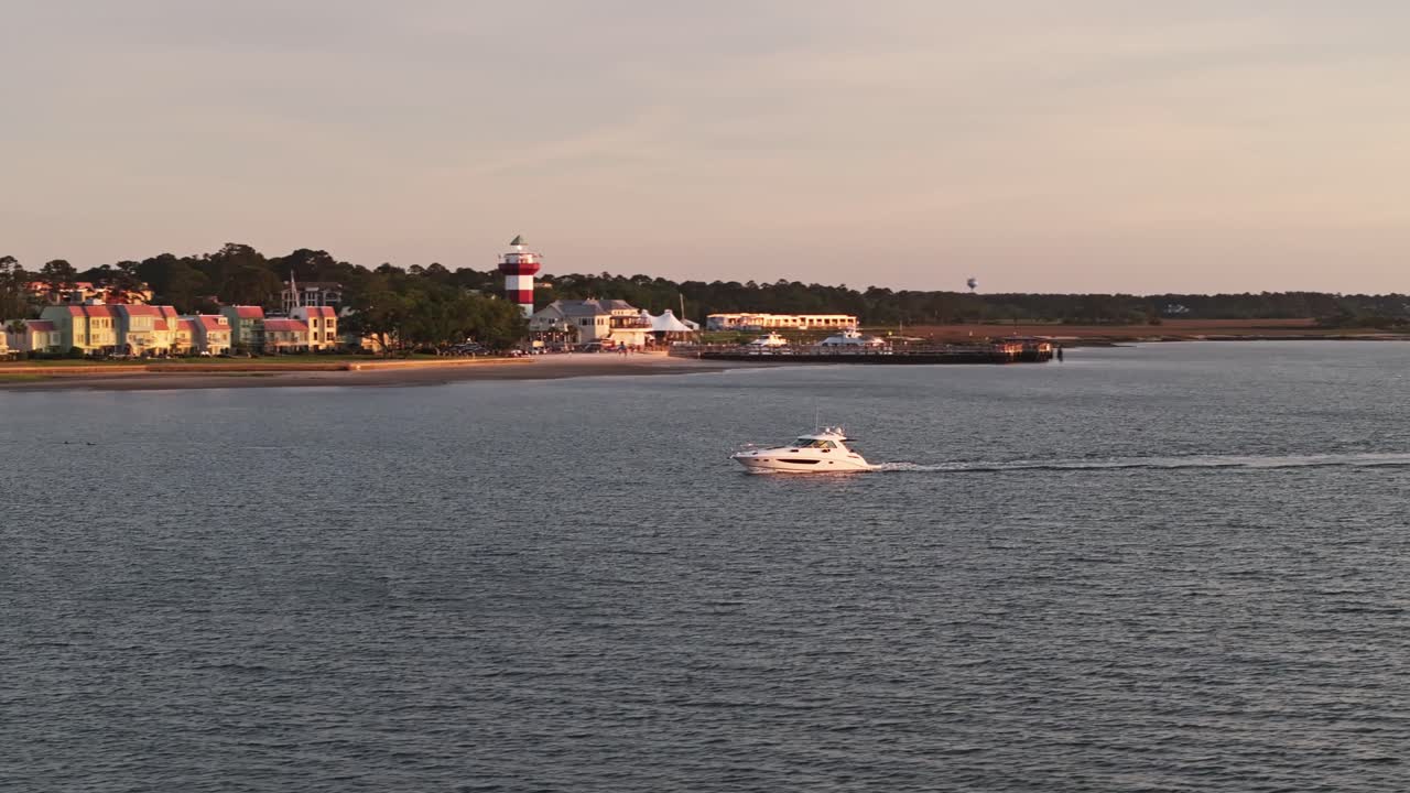 Sunset light over South Carolina coast, calm water surrounds docked fishing boats, aerial telephoto orbit