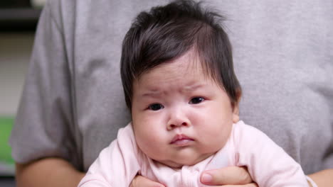 엄마의 무에 앉아 있는 신생아는 엄마의 품에서 움직이려고 휘두르고 펴고 있다.